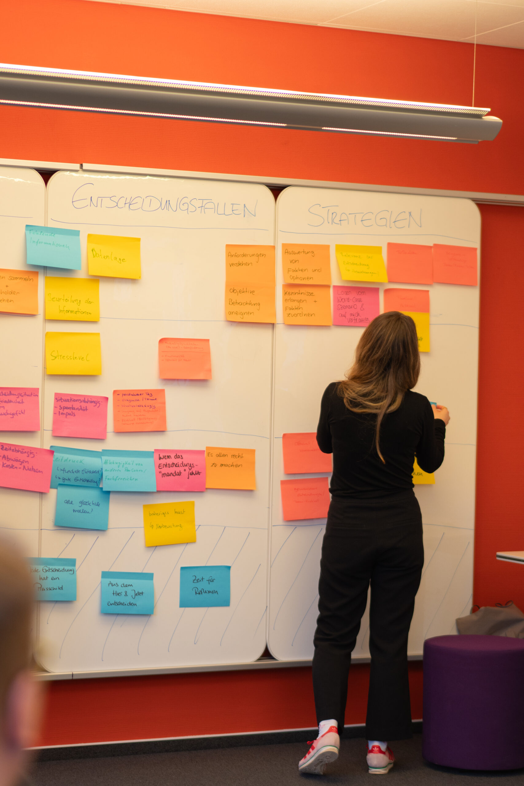 Eine Referentin steht vor einer vollen Wand mit Post-its